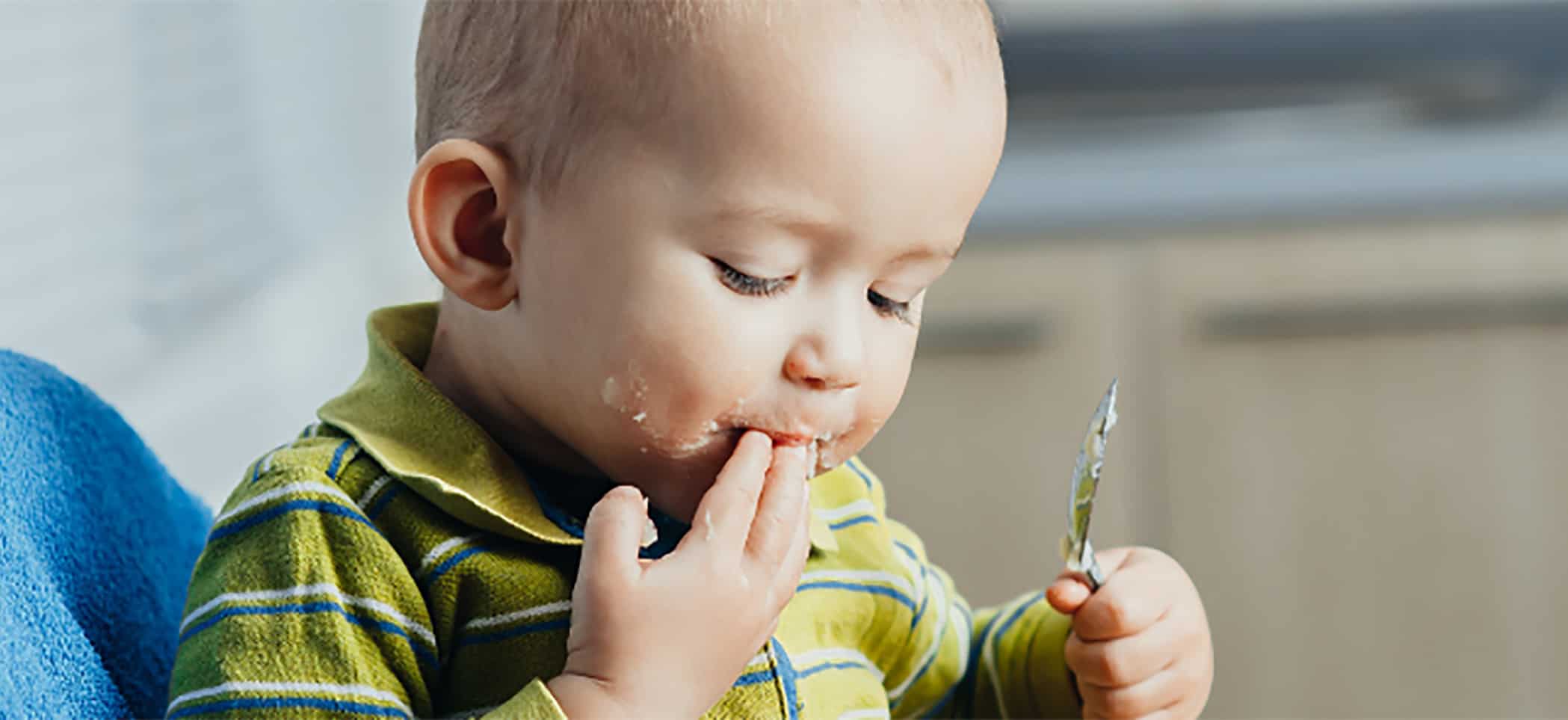 a toddler feeds himself